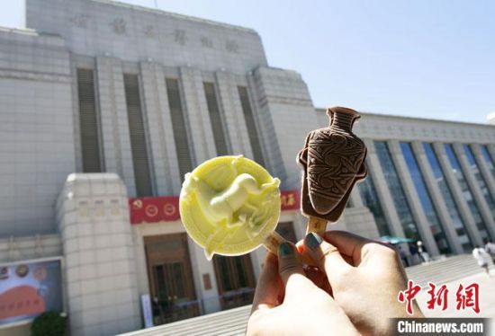 2021年7月30日，游客手拿“銅奔馬”“彩陶瓶”造型的雪糕，在甘肅省博物館前拍照打卡?！「哒?攝