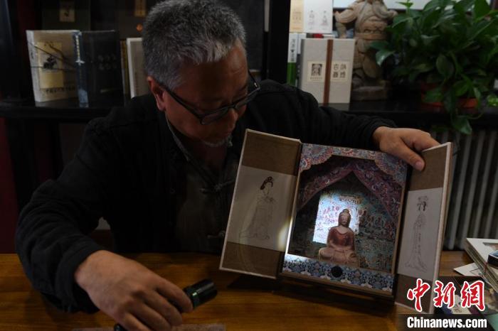 圖為讀者出版集團(tuán)讀者晉林工作室獨(dú)立出品人徐晉林，展示互動(dòng)性強(qiáng)的敦煌題材手工書。(資料圖) 楊艷敏 攝