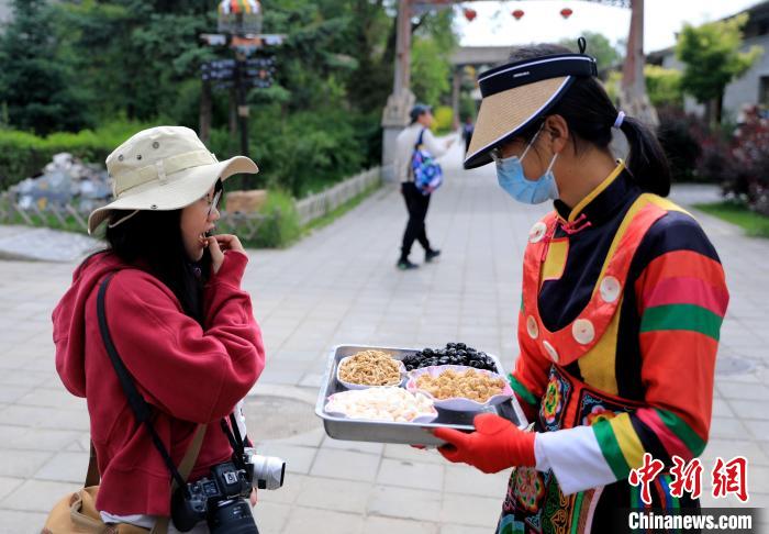 圖為身穿土族服飾的女性介紹當(dāng)?shù)靥厣〕?。　薛?攝