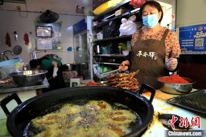 圖為平安驛·河湟民俗文化體驗(yàn)地內(nèi)的商戶炸干板魚?！⊙Φ?攝